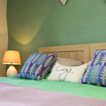 colourful bed sheets and pillow, with green wall behind