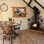 byrddau a chadeiriau pren gyda drych uwchben wrth ymyl llosgwr coed