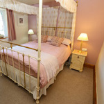 gwely dwbl pedwar postyn mewn ystafell wely binc