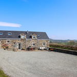 adeilad carreg mawr a mynyddoedd yn y cefndir