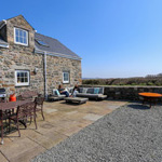 adeilad carreg mawr a dwy ddynes yn eistedd tu allan