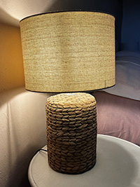 Woven rattan table lamp with beige fabric shade.